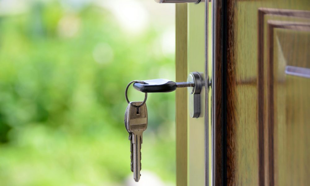 Key inserted in door lock against a blurred green background, symbolizing security and real estate.