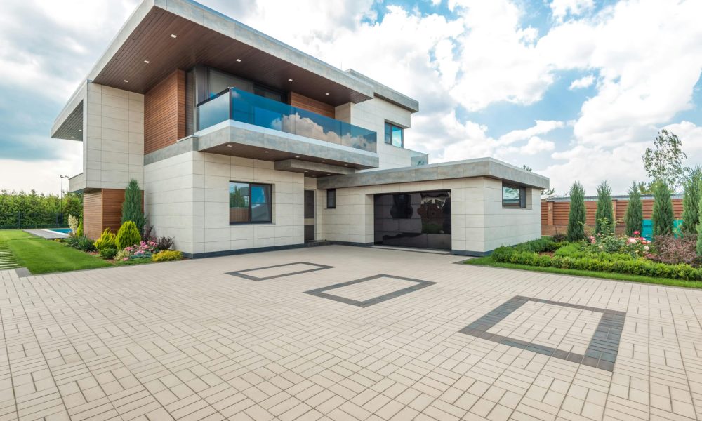 Elegant modern house exterior with lush greenery and ample driveway space.